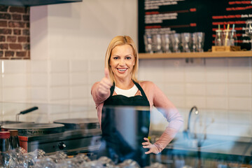 A pancake shop worker is standing in kitchen and showing thumbs up.
