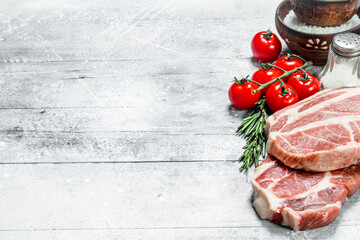 Raw pork steaks with tomatoes and hot chili peppers.