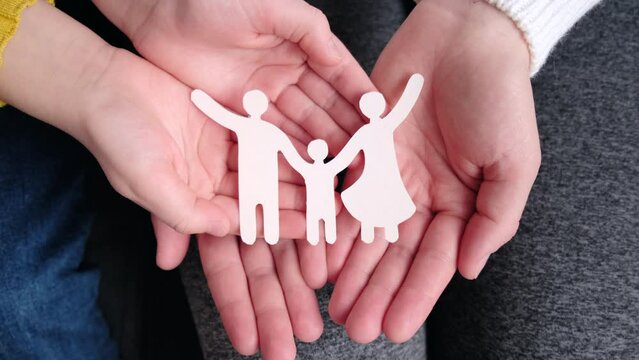 Top view close up of hands holding paper family cutout, foster care, homeless support, social distancing, world mental health day. Autism support, homeschooling education, parents day concept