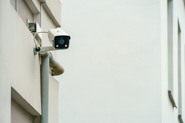A modern surveillance camera mounted on the wall of a guarded building, close-up. Security and theft protection systems. Protection of private territory, banking system and personal belongings.