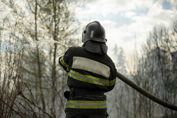 Firefighter puts out fire in woods. Lifeguard pours water.