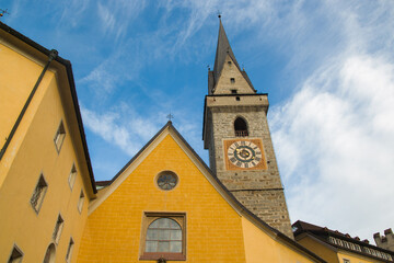 Fototapeta na wymiar View of bell tower with clock in the historic center of Brunico town in Alto Adige, Italy