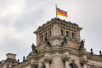 The Reichstag in Berlin with tower and figures and the flag of Germany