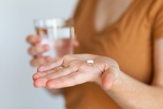 Person holding oxycodone pain-relief tablet and glass of water