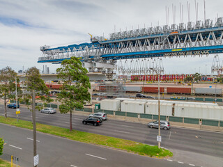 A large suspension crane building an elevated freeway next to a busy highway