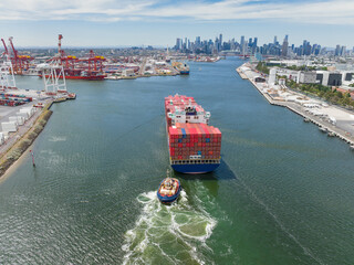 Aerial view of a tugboat moving a large cargo ship up a river