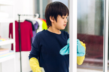 Kid little asian boy son having fun doing household cleaning and washing in protective gloves using...