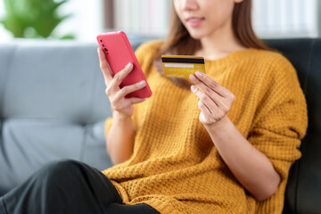 Young Asian woman is using credit card to make online purchases on mobile phone, online shopping.