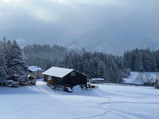 Old traditional swiss rural architecture and alpine livestock farms in the winter ambience over the Lake Walen or Lake Walenstadt (Walensee) and in the Swiss Alps, Amden - Switzerland / Schweiz