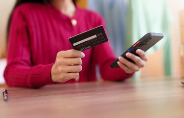Close-up woman using credit card to make purchases on mobile phone, online shopping concept.