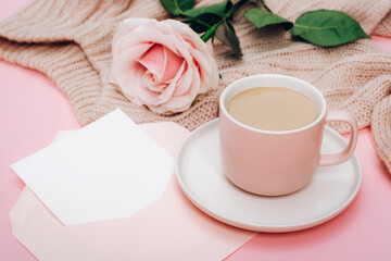 A coffee cup, pink rose and envelope with blank card. Holiday concept. Top view, mockup
