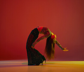 Flexibility and passion. Portrait of young girl dancing heels dance over red background in neon light. Concept of modern dance style