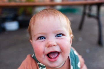 Bright blue eyes and huge smile on baby playing outdoors