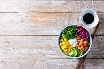 Poke bowl with rice, salmon,cucumber,mango,onion,wakame salad, poppy seeds ands sunflowers seeds on...