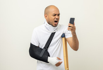 Depressed upset man suffering from pain. Broken arm. Asian man put on plaster bandage cast splint...
