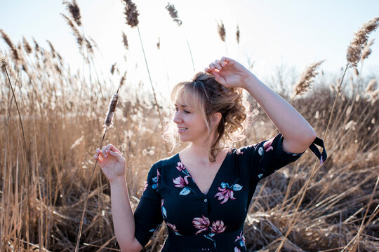 woman dancing and smiling in a summer dress at sunset in a field