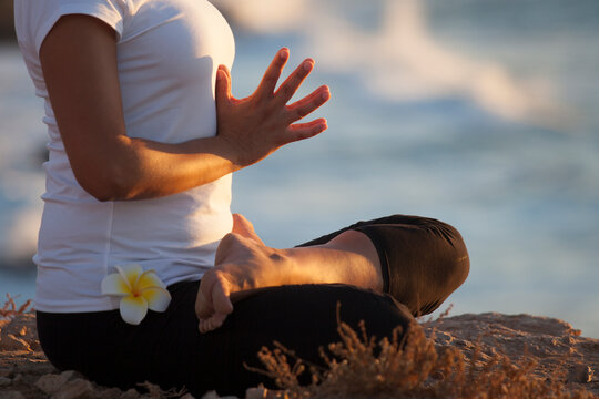 Yoga. Detail of a girl /woman in lotus position with the ocean in the background. Fuerteventura, Canary Islands