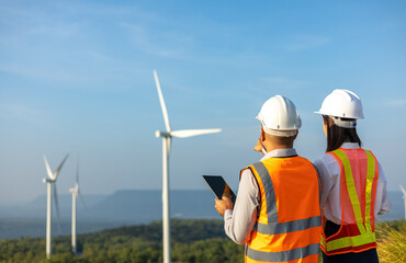 Two Engineer man and woman working at windmill farm Generating electricity clean energy. Wind...
