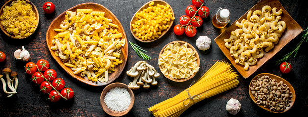 Assortment of different types of raw pasta with mushrooms, tomatoes and garlic.