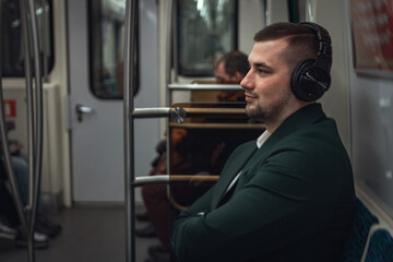 Fototapeta na wymiar man young male caucasian passenger one person positively cheerful listens to music in headphones, smiles and go by subway transport in the morning. concept subscription to music.