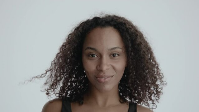 Attractive African-American Black female blows a kiss into camera against white background. Shot with ARRI Alexa Mini LF