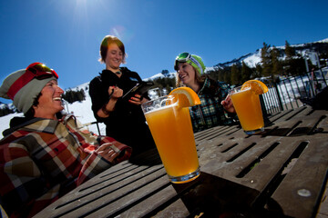 Young couple ordering food and beer on an outdoor patio at a ski resort.