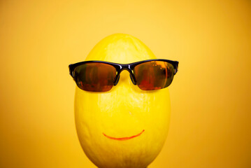 funny happy face melon in sunglasses on yellow background, abstraction