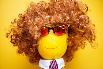 funny happy melon face in sunglasses and a wig on a yellow background, abstraction