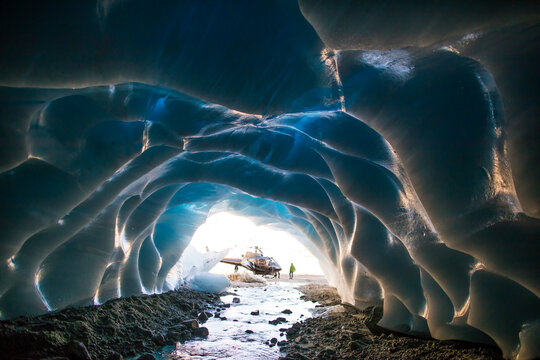 Helicopter parked outside of a glacial ice cave.