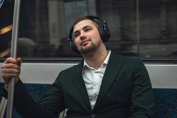 man young male caucasian passenger one person positively cheerful listens to music in headphones, smiles and go by subway transport in the morning. concept subscription to music.