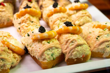 Typical snack of Basque Country, pinchos or pinxtos, small piece of bread with different fish and sea food toppings, served in bar in San-Sebastian or Bilbao, Spain