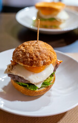 Tasty burger with white crispy ban, beef burger, egg, green lettuce and cheese