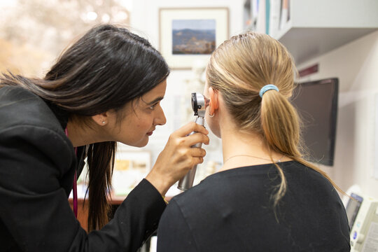 female doctor checking the woman's ear with an otoscope in a clinic