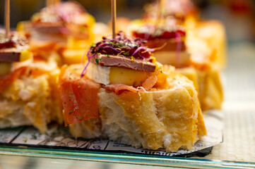 Typical snack of Basque Country, pinchos or pinxtos skewers with small pieces of bread, sea food, eggs, cheese, jamon served in bar in San-Sebastian or Bilbao, Spain
