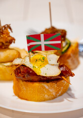 White board with typical snack and flag of Basque Country, pinchos or pinxtos skewers with small pieces of bread, courgette, sea food, eggs, cheese, served in bar in San-Sebastian or Bilbao