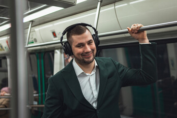 Fototapeta premium man young male caucasian passenger one person positively cheerful listens to music in headphones, smiles and go by subway transport in the morning. concept subscription to music.