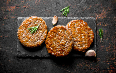 Cutlets on a stone Board with cloves of garlic and rosemary.