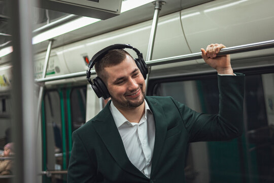 man young male caucasian passenger one person positively cheerful listens to music in headphones, smiles and go by subway transport in the morning. concept subscription to music.