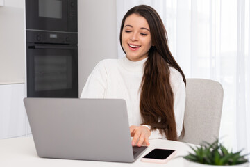 Cheerful woman laughs at online meeting with colleagues looking in Notebook. Young employee with long loose hair sits in chair smiling closeup slow motion