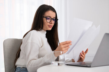 Happy millennial woman reading papers and working in the office.