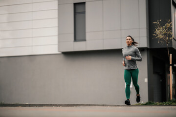 Fototapeta na wymiar A fit sportswoman is running fast on a rainy day on the street.