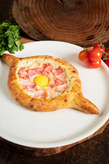 Adjarian Khachapuri traditional Georgian dish with sulguni cheese filled bread and egg yolk on tablecloth side view