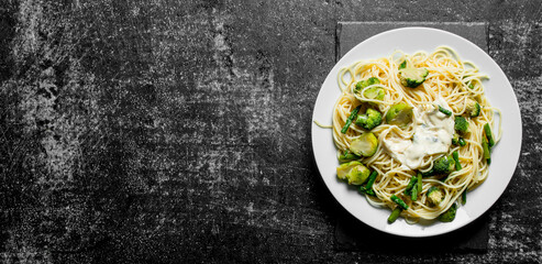 Pasta with vegetables and sauce on a plate.