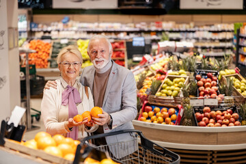 A healthy senior couple is purchasing fruits at supermarket.