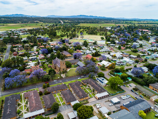 View of residential part of small town and church in November with flowering jacaranda trees