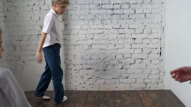 Teenage boy in white shirt does cartwheel on wooden stage in corner of photo studio at family gathering