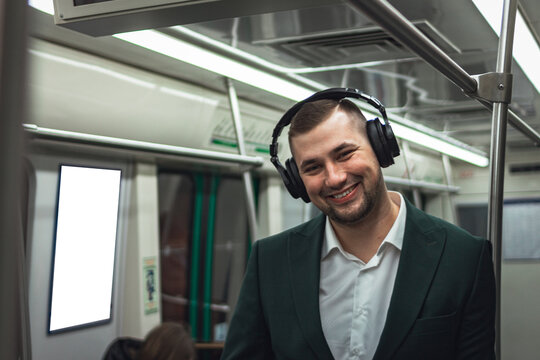 man young male caucasian passenger one person positively cheerful listens to music in headphones, smiles and go by subway transport in the morning. concept subscription to music. copy space.