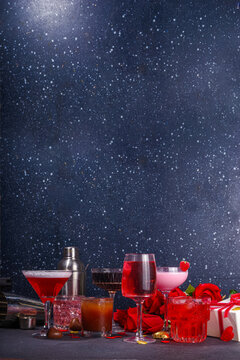 Valentine day romantic bar background. Set various red, pink, chocolate alcohol drinks for Valentine day party or dating, in different cocktail glasses with rose flower bouquet, heart decor, gift box
