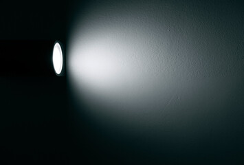 Spotlight, lamp with beam of light on the wall in dark room