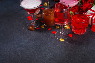 Valentine day romantic bar background. Set various red, pink, chocolate alcohol drinks for Valentine day party or dating, in different cocktail glasses with rose flower bouquet, heart decor, gift box